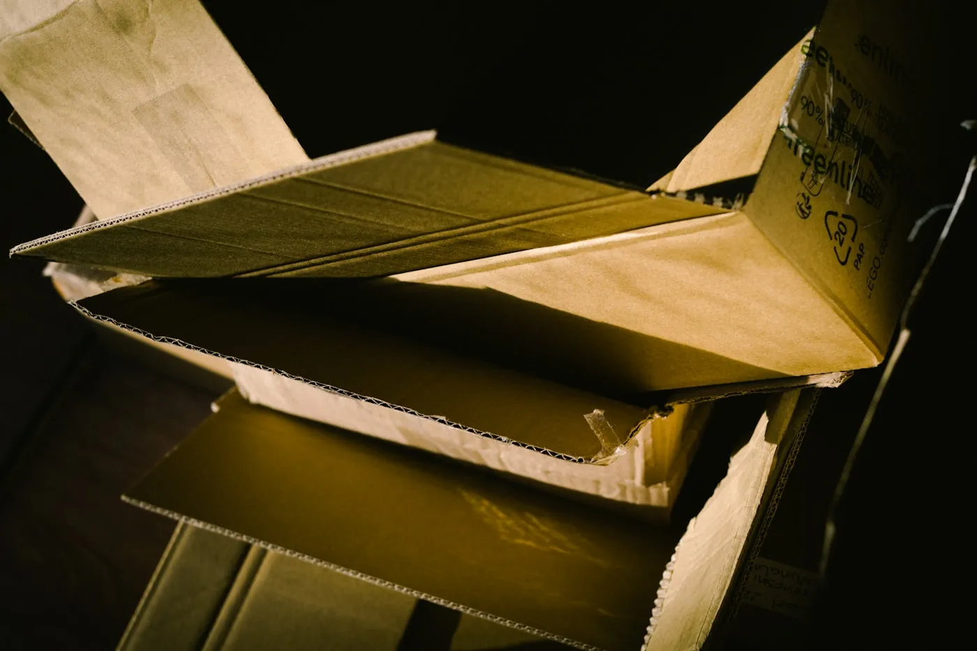 Close-up of an open corrugated cardboard box showing recycling marks and fluted board structure