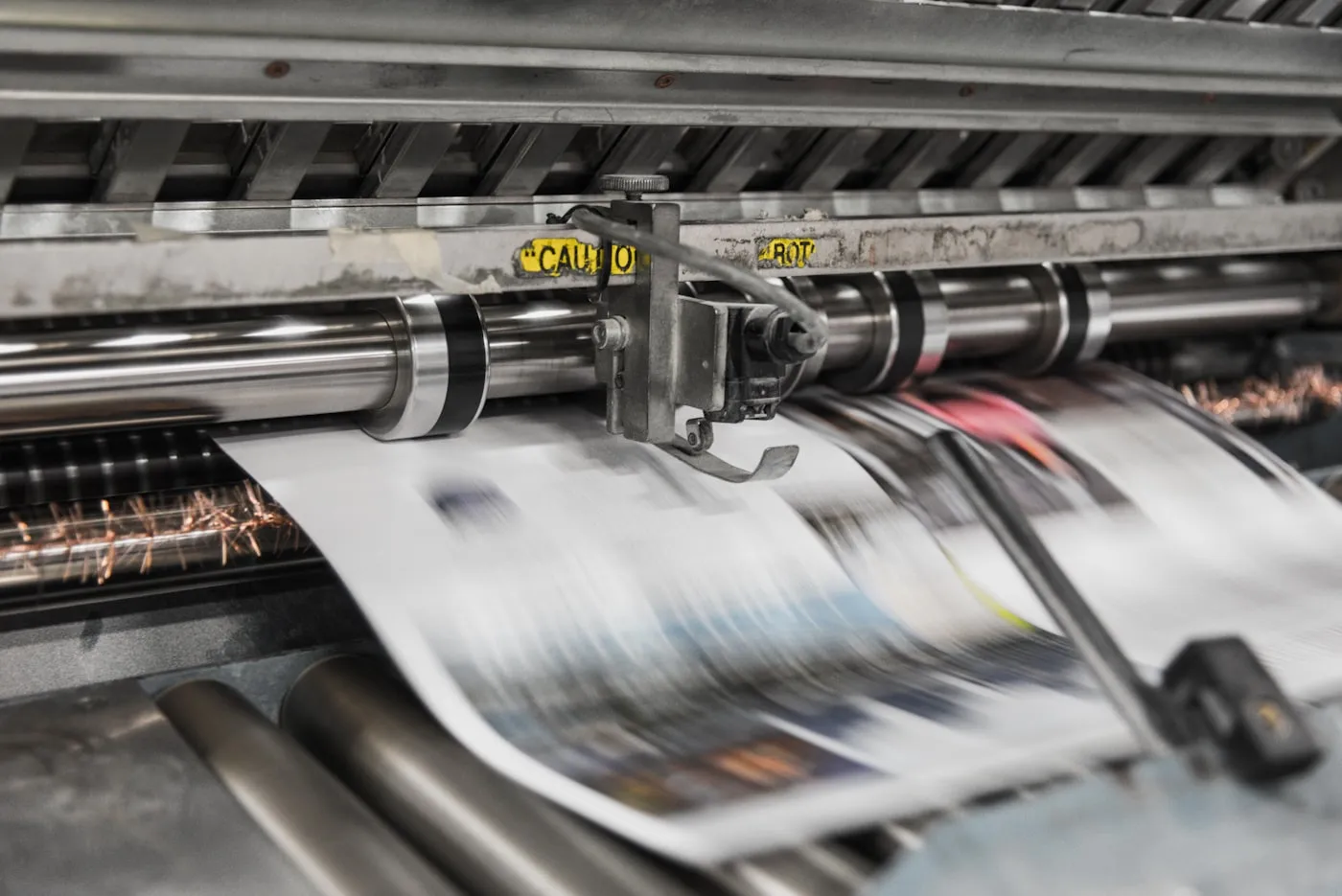 Industrial printing press running printed sheets through its rollers